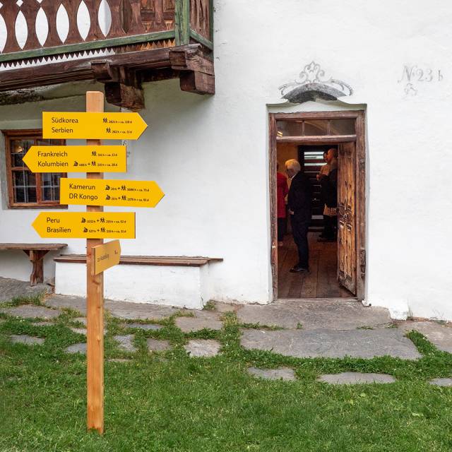 Der Wegweiser am Eingang des Gedächtnisspeichers weist den Weg in die Ausstellung, aber auch über die nächste Bergkette hinaus in Weltregionen, die mit dem Ötztal verentzt sind.